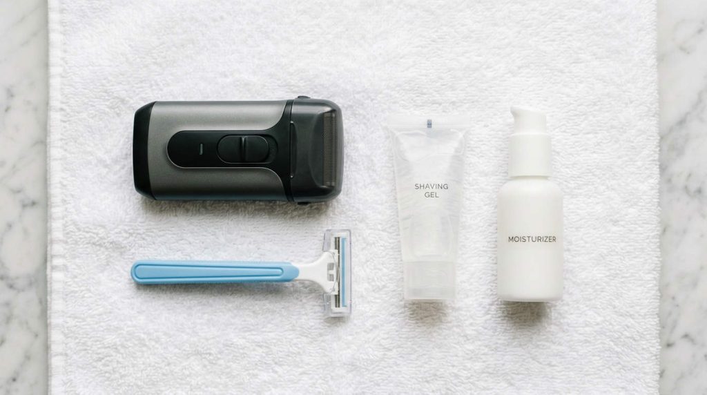 Electric shaver, razor, shaving gel, towel, and lotion laid out for a safe first shave.